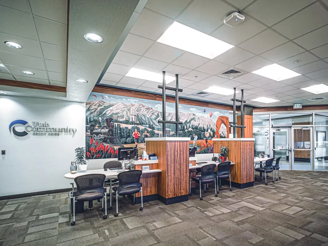 Credit union branch with a Utah Community Credit Union sign, teller counters and a mountain mural