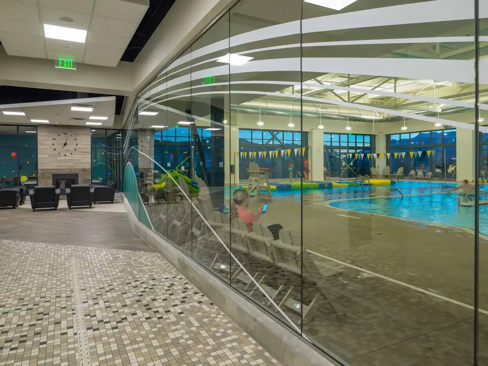 Lobby lounge with a fireplace beside a curved glass wall that looks onto the pool deck.