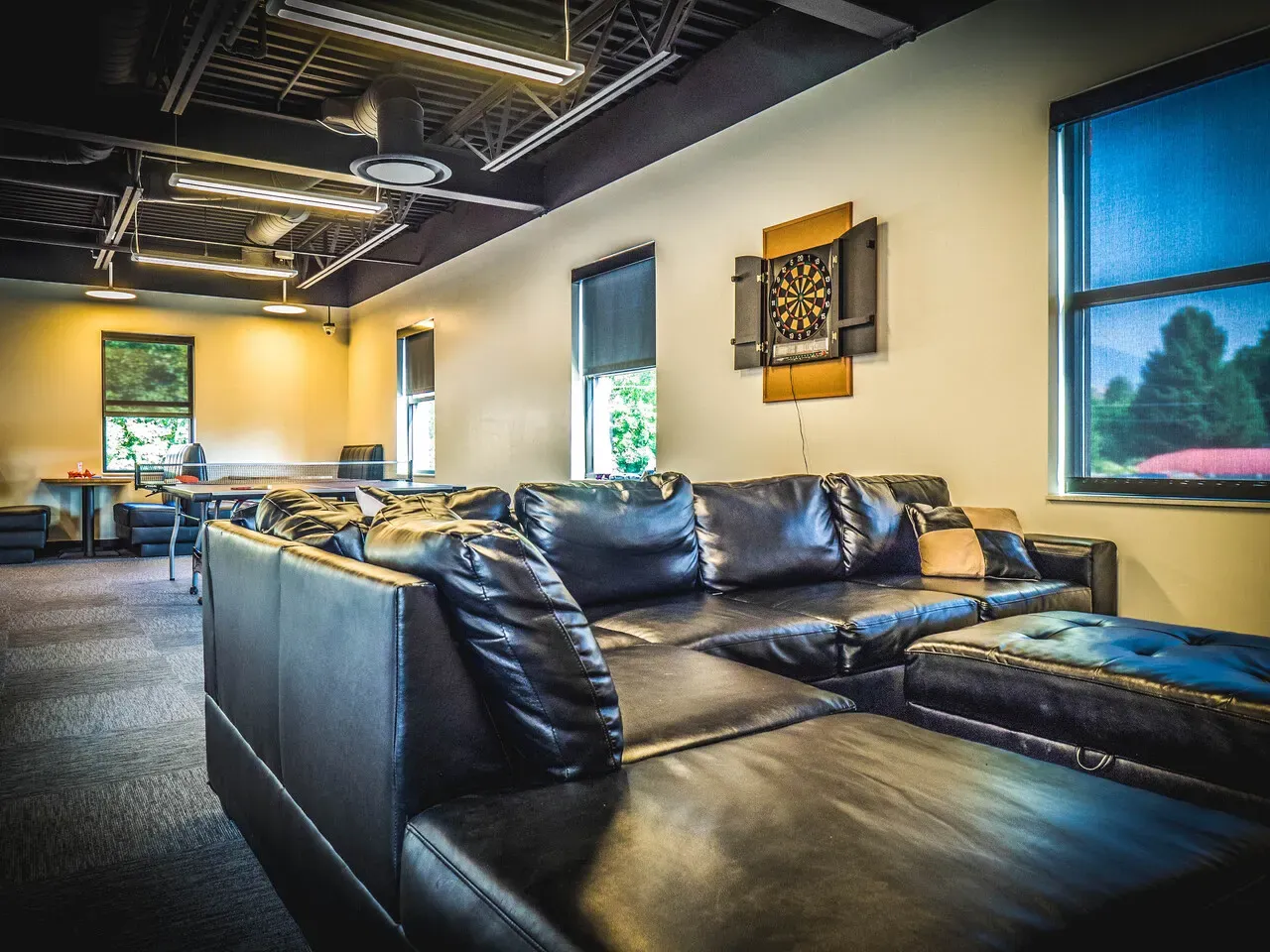 Leather sectional sofa in a lounge with a dartboard on the wall