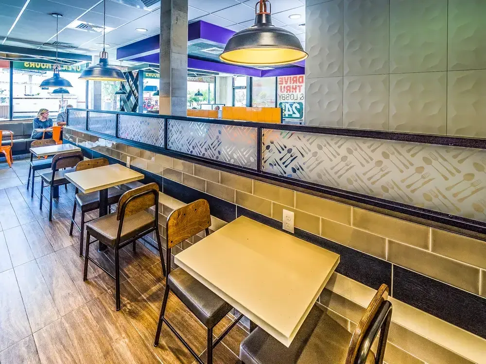 Dining area with built-in bench seating, tables and a patterned glass divider.