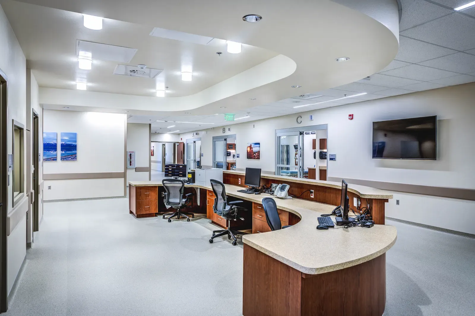 Curved wood and laminate nurses' station with computer monitors and chairs