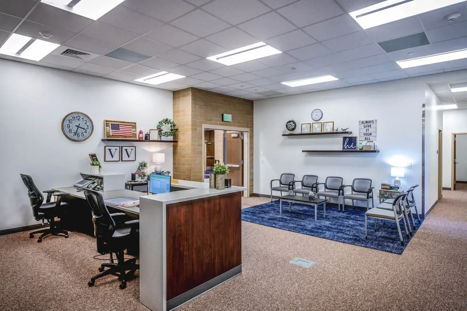 Front office with a reception desk and a waiting area with chairs and a blue rug.