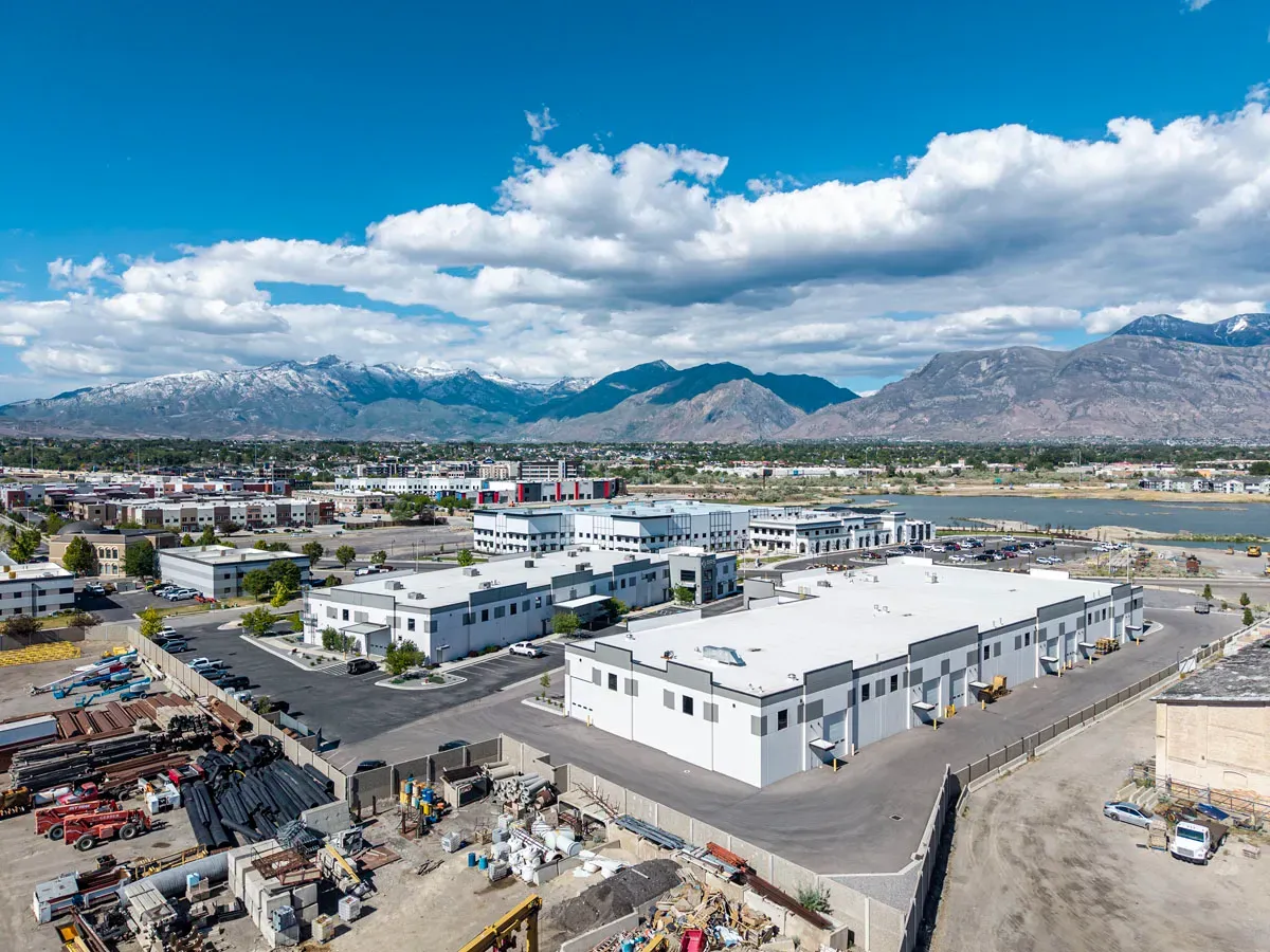 Aerial view of the warehouse roof and surrounding buildings with snow-capped mountains behind.