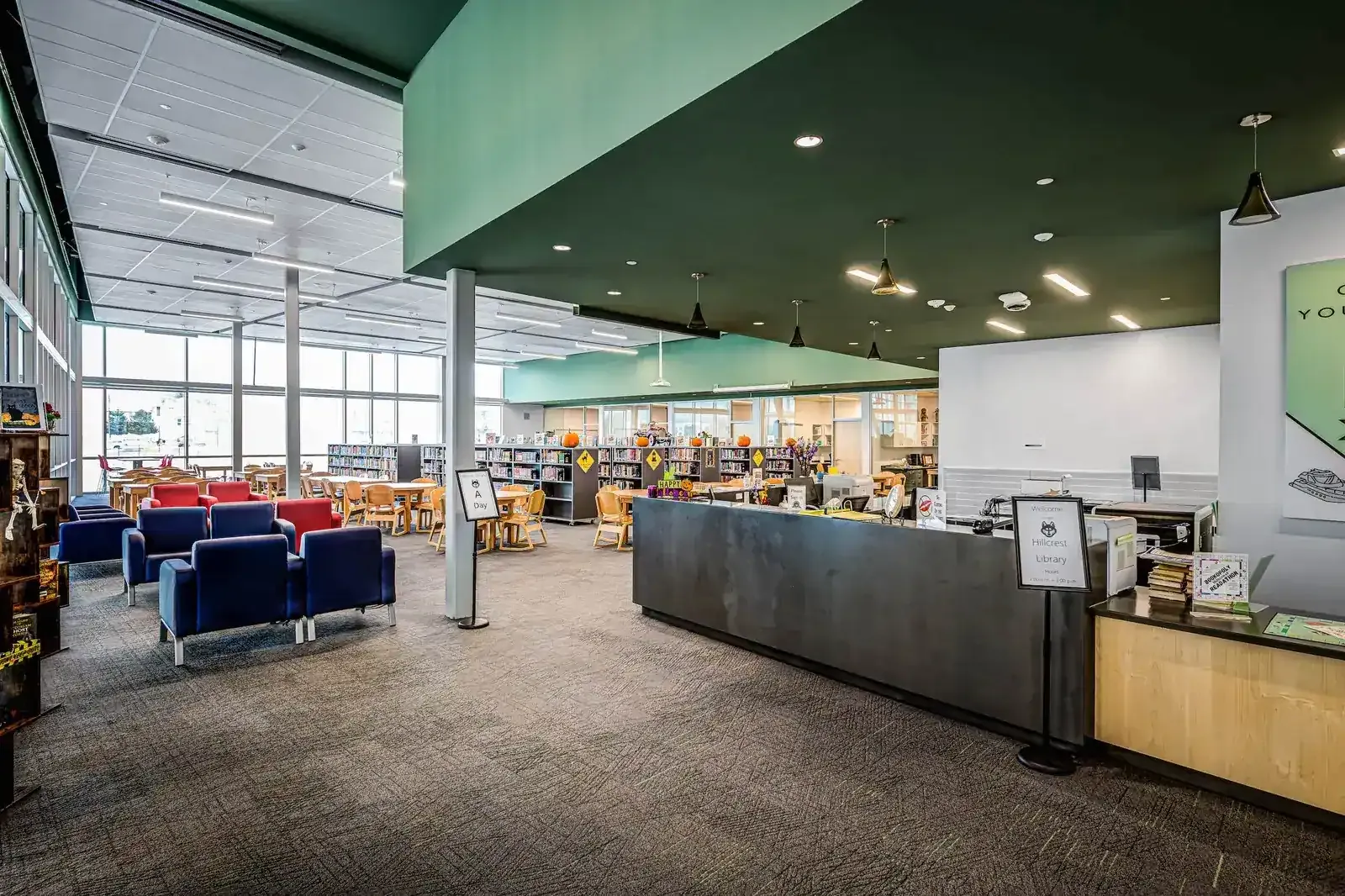 Library with a curved service desk, blue seating and green ceiling soffits