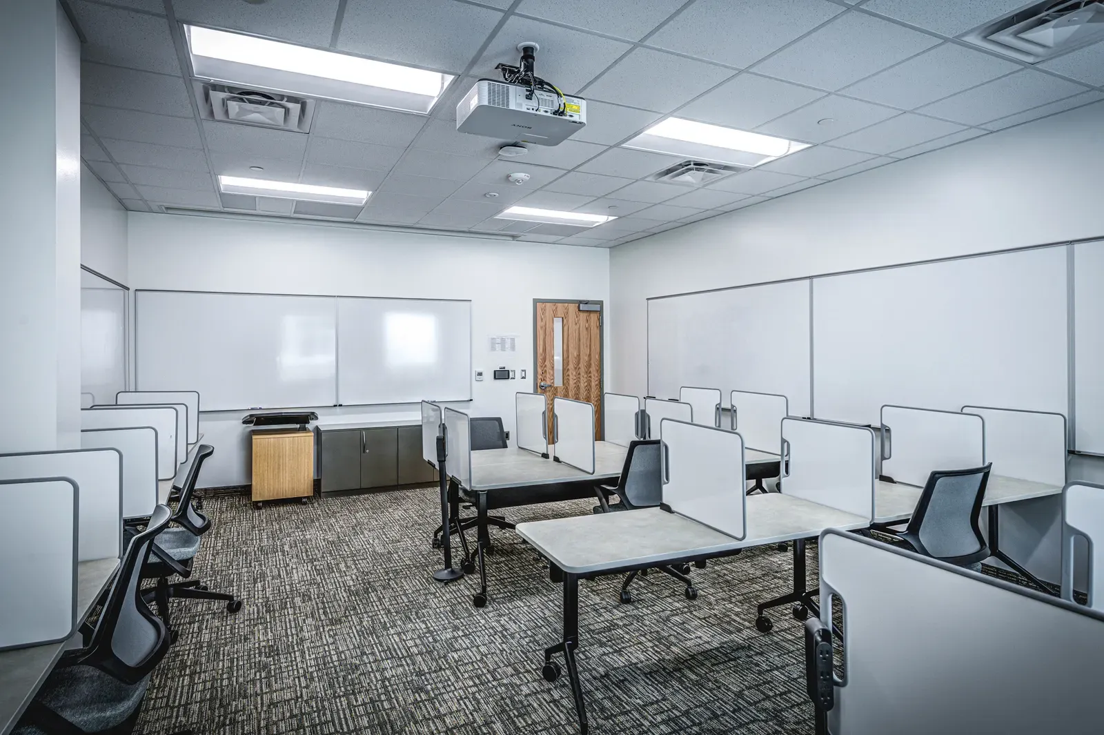 Classroom with whiteboards and tables fitted with small privacy dividers