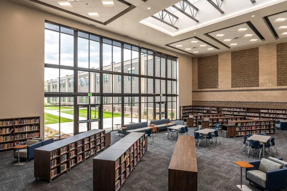 Library with tall windows, low book stacks, and reading tables