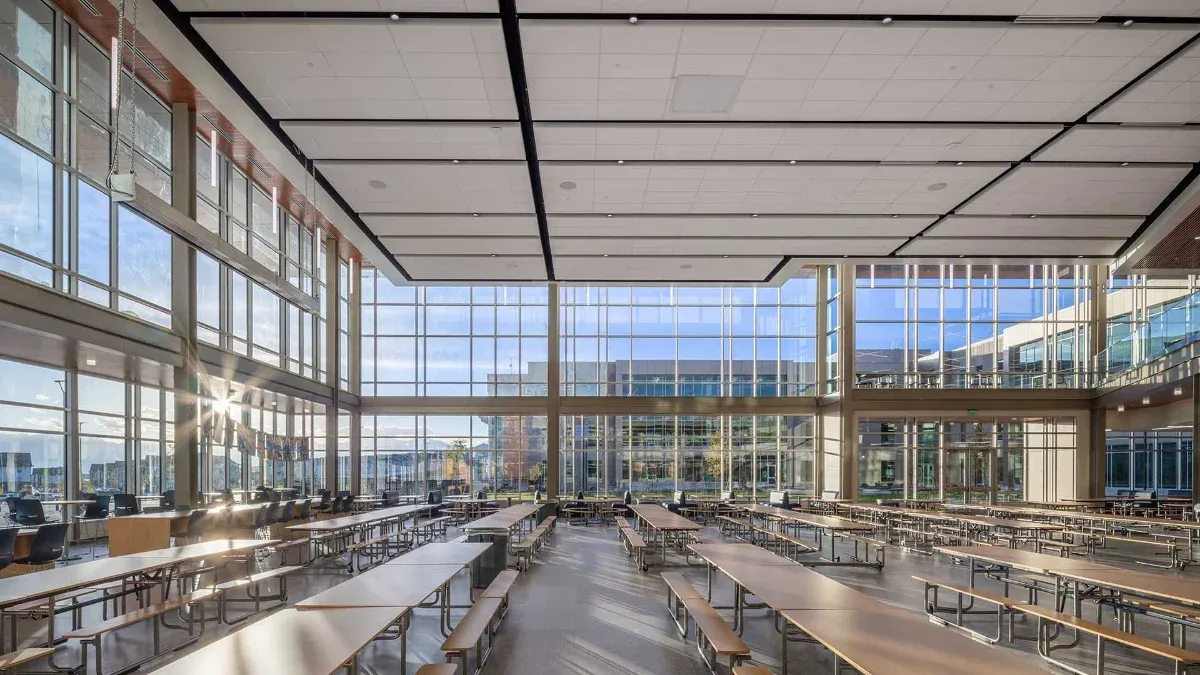 Two-story commons with long dining tables and floor-to-ceiling windows