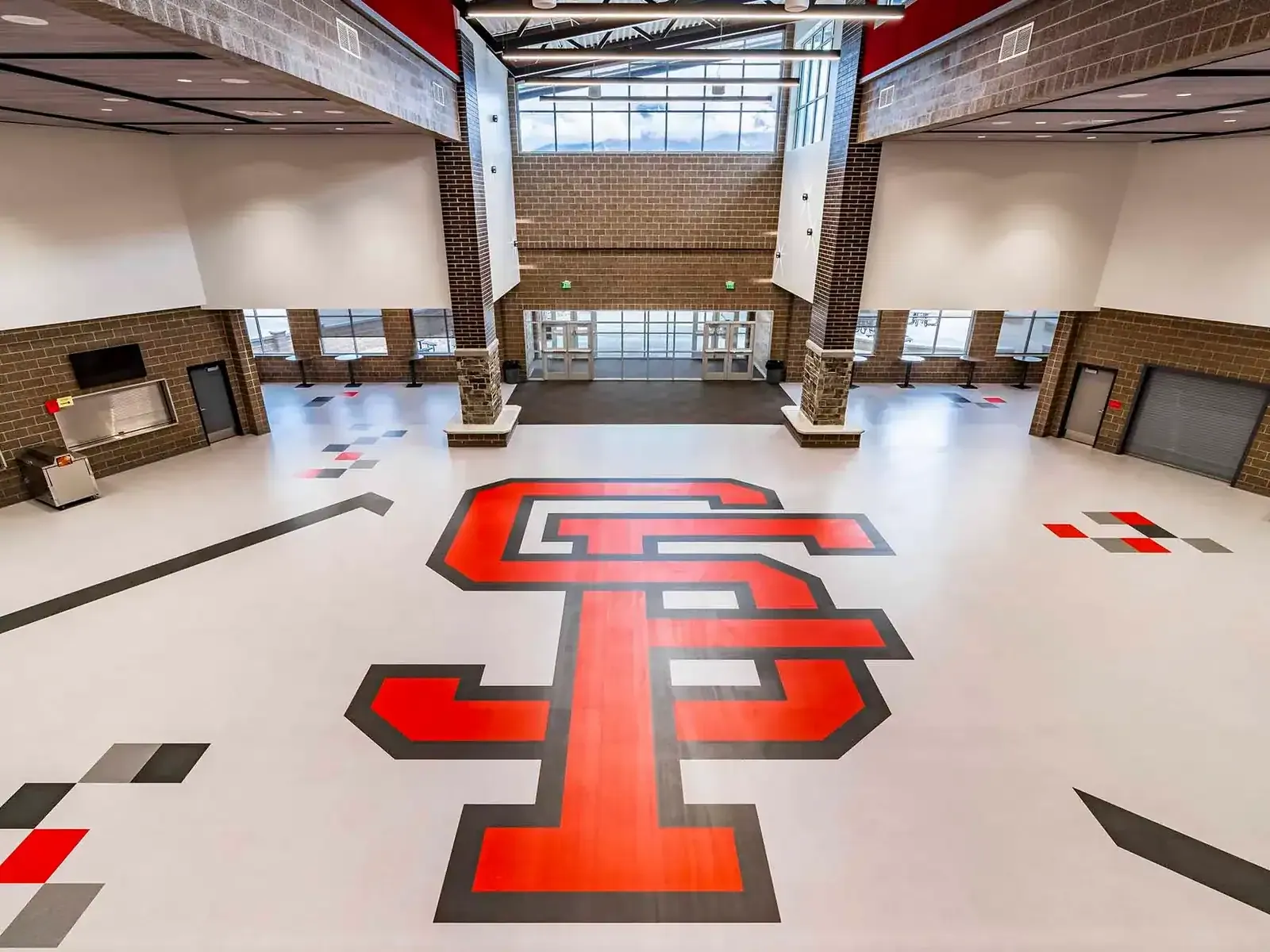 Commons floor seen from above with a large red SF logo inlaid in the flooring and brick and stone columns.