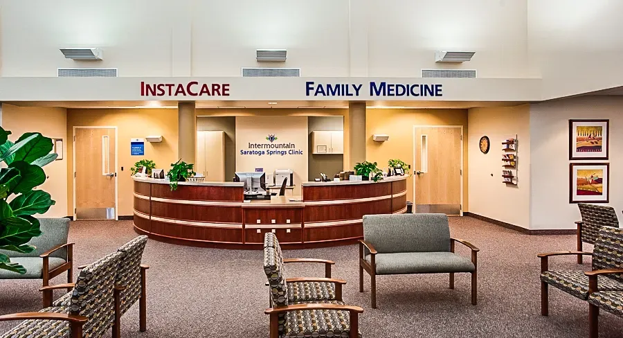 Reception desk beneath InstaCare and Family Medicine signs, with upholstered waiting chairs in front