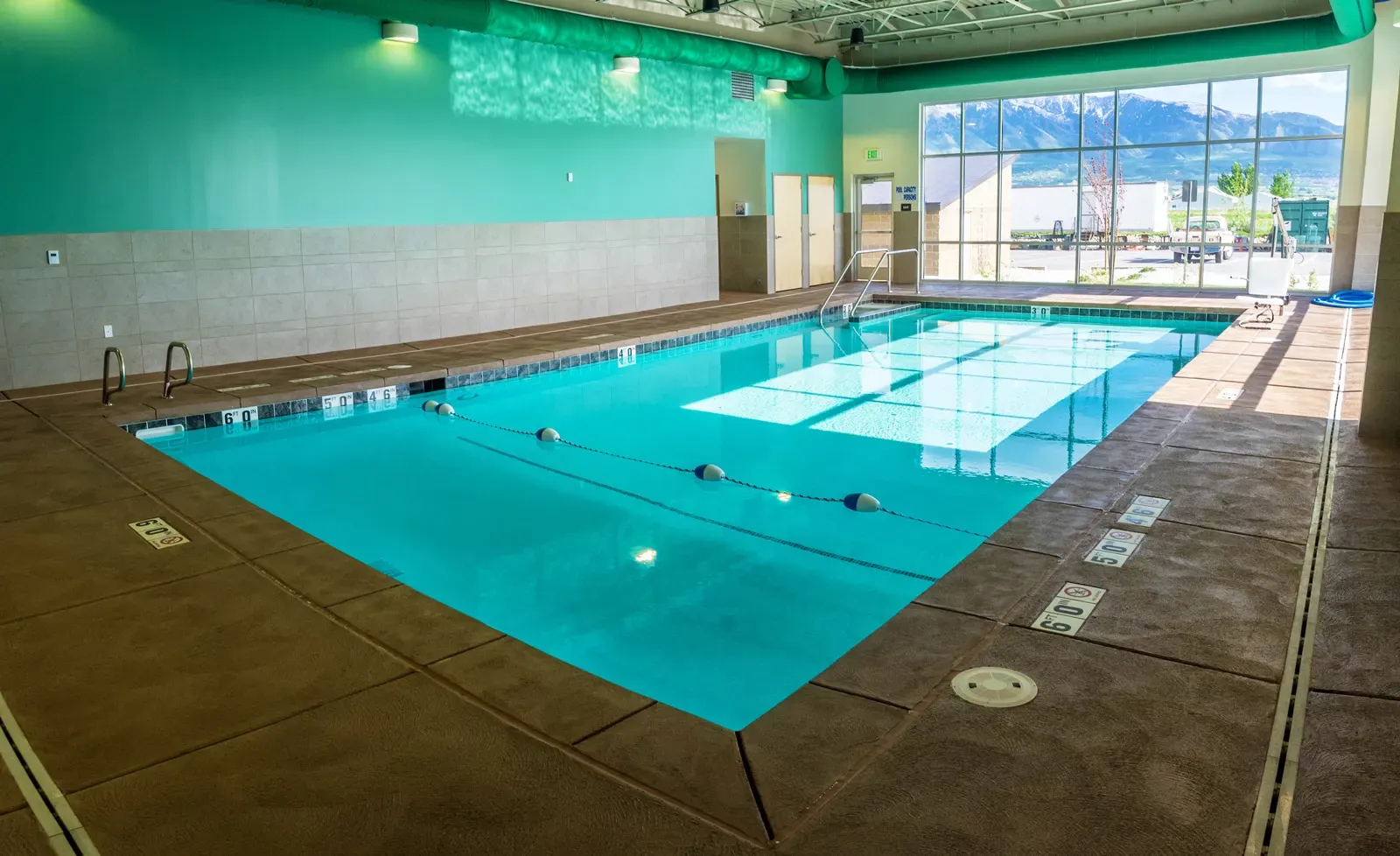 Indoor pool with teal walls and a large window looking onto the mountains.