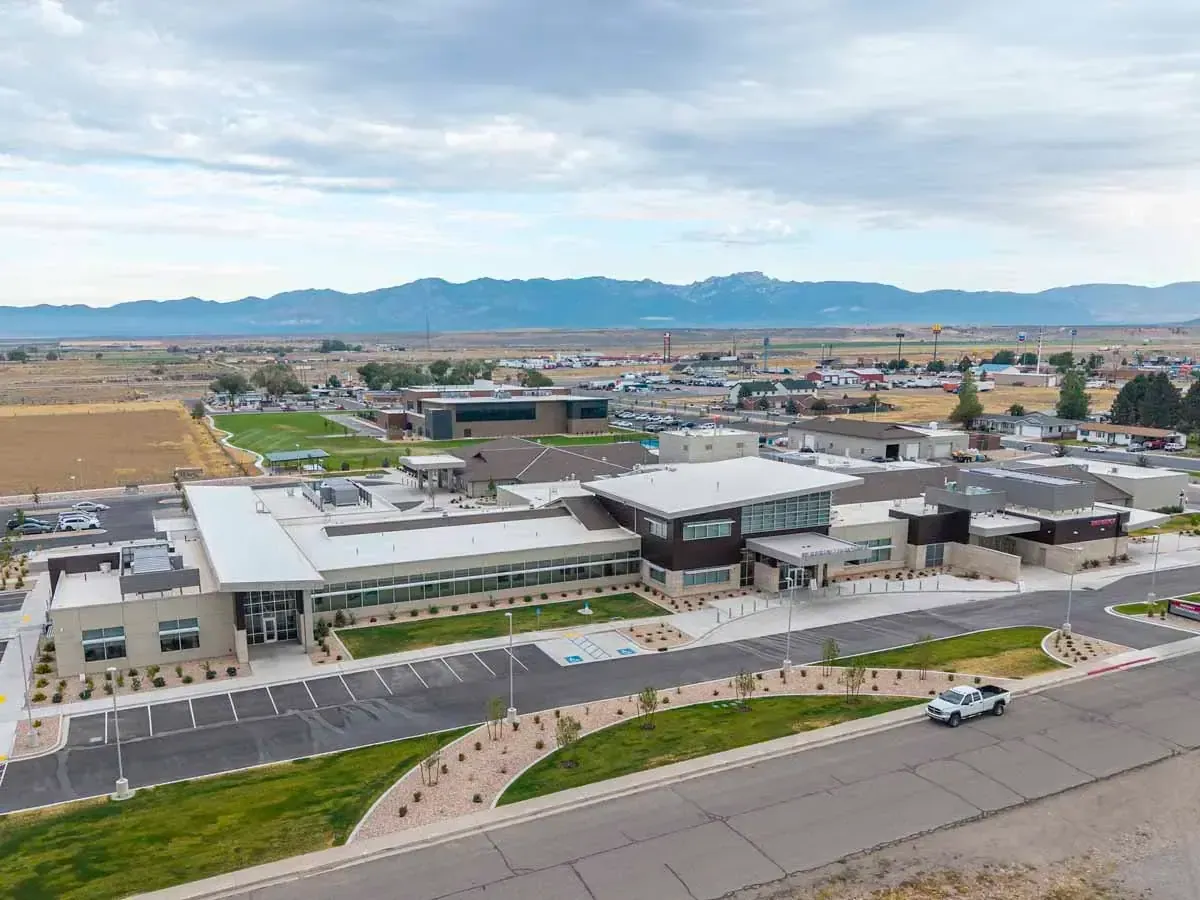 Aerial view of the hospital campus and its parking lots, with farmland and mountains in the distance.