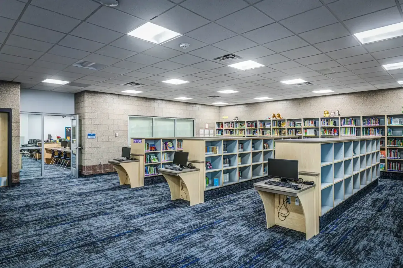 Media center with low shelving, computer stations and a wall of books.