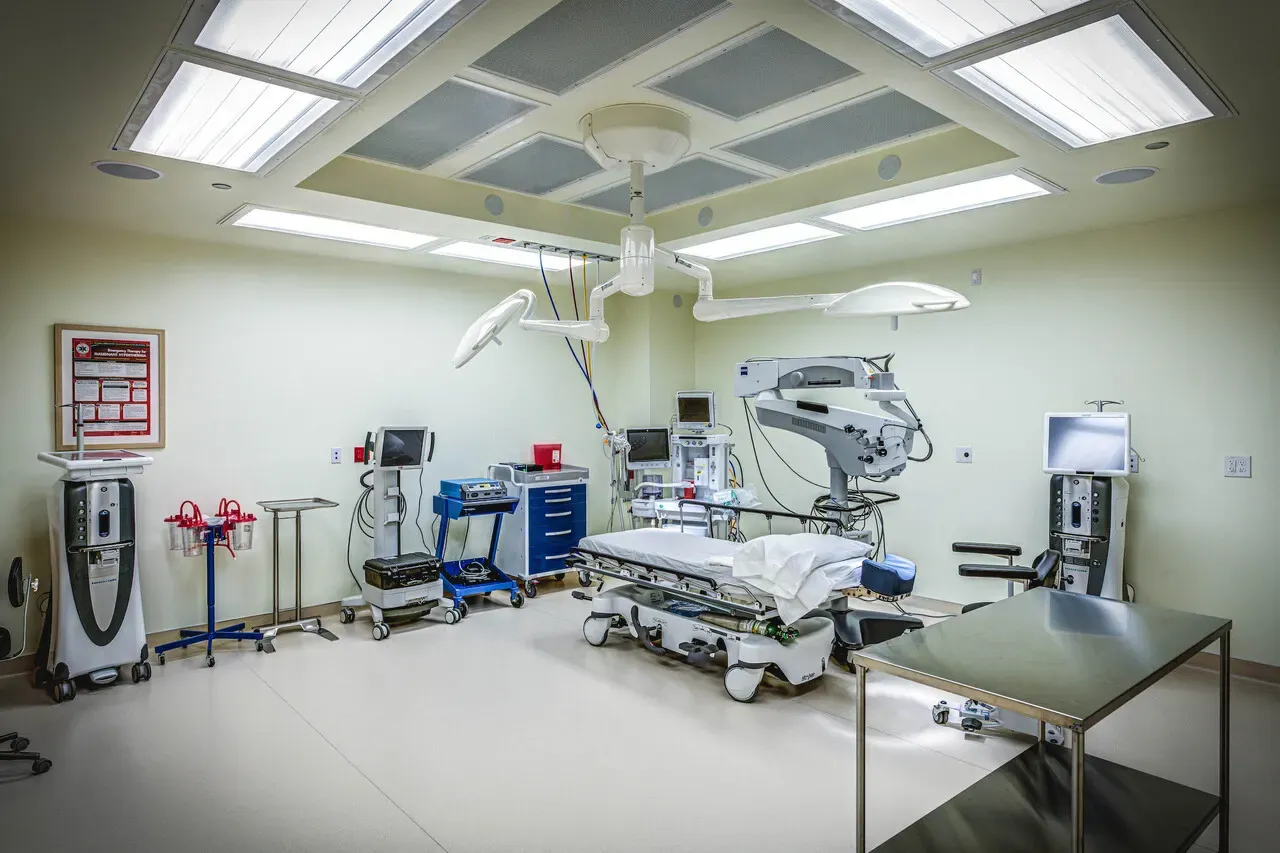 Operating room with a stretcher bed, ceiling-mounted lights, and monitoring equipment.