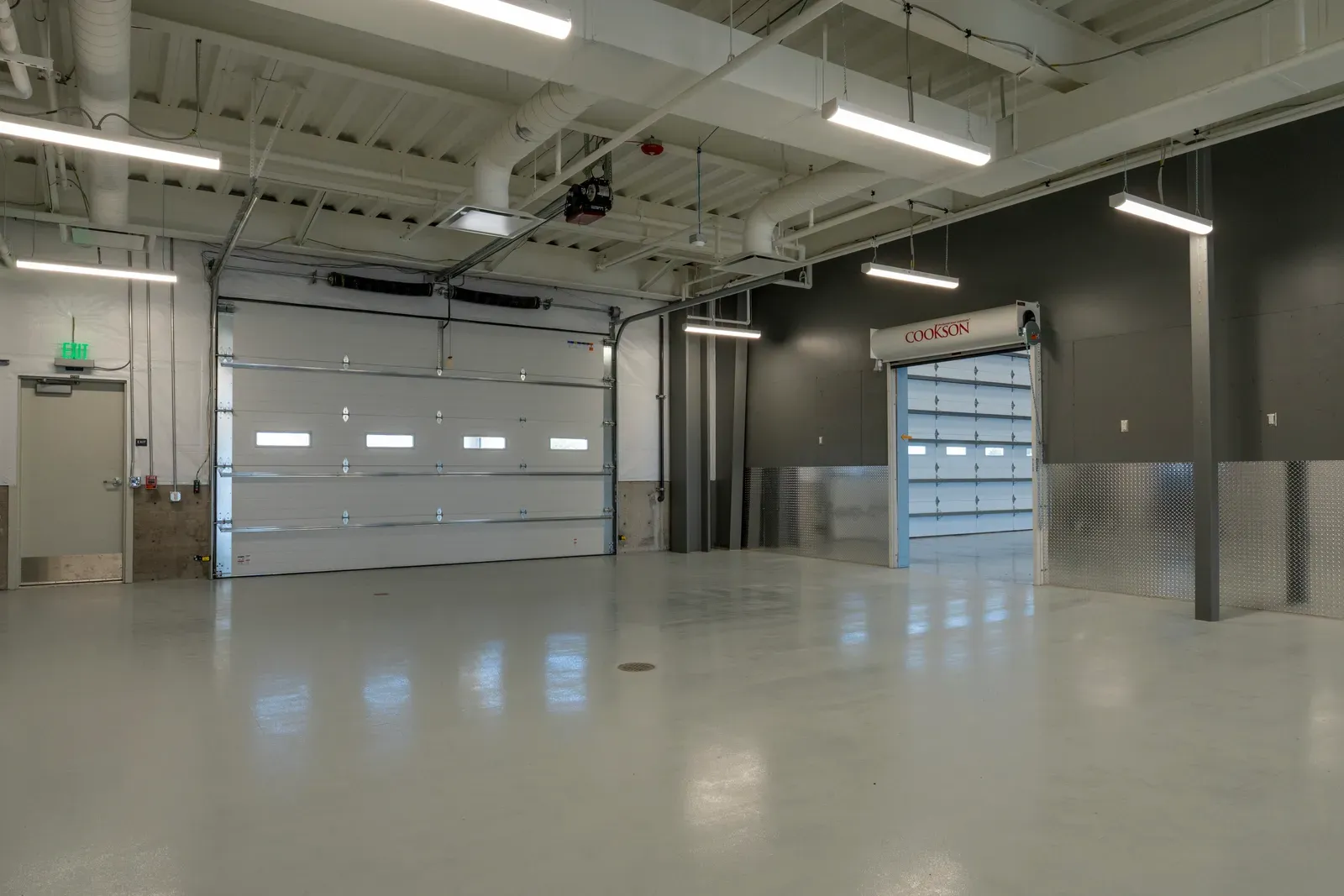 Shop bay with an overhead door, a high-speed roll-up door and diamond-plate wall protection.