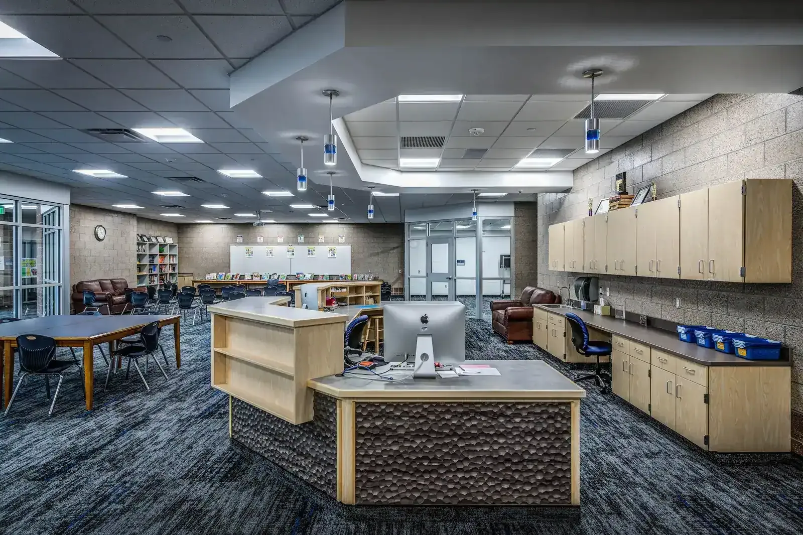 Media center circulation desk with study tables and a reading nook behind it.
