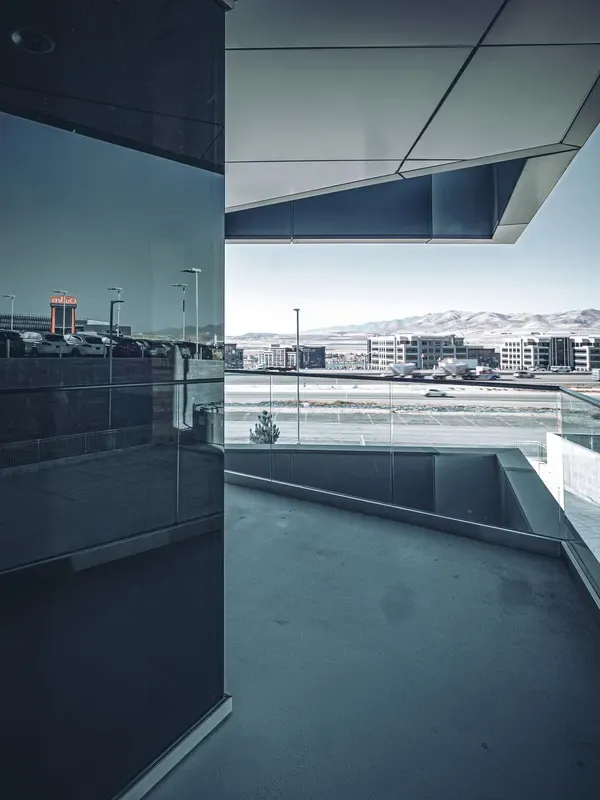 Balcony with a glass railing and a reflective glass wall, looking out across the valley toward the mountains