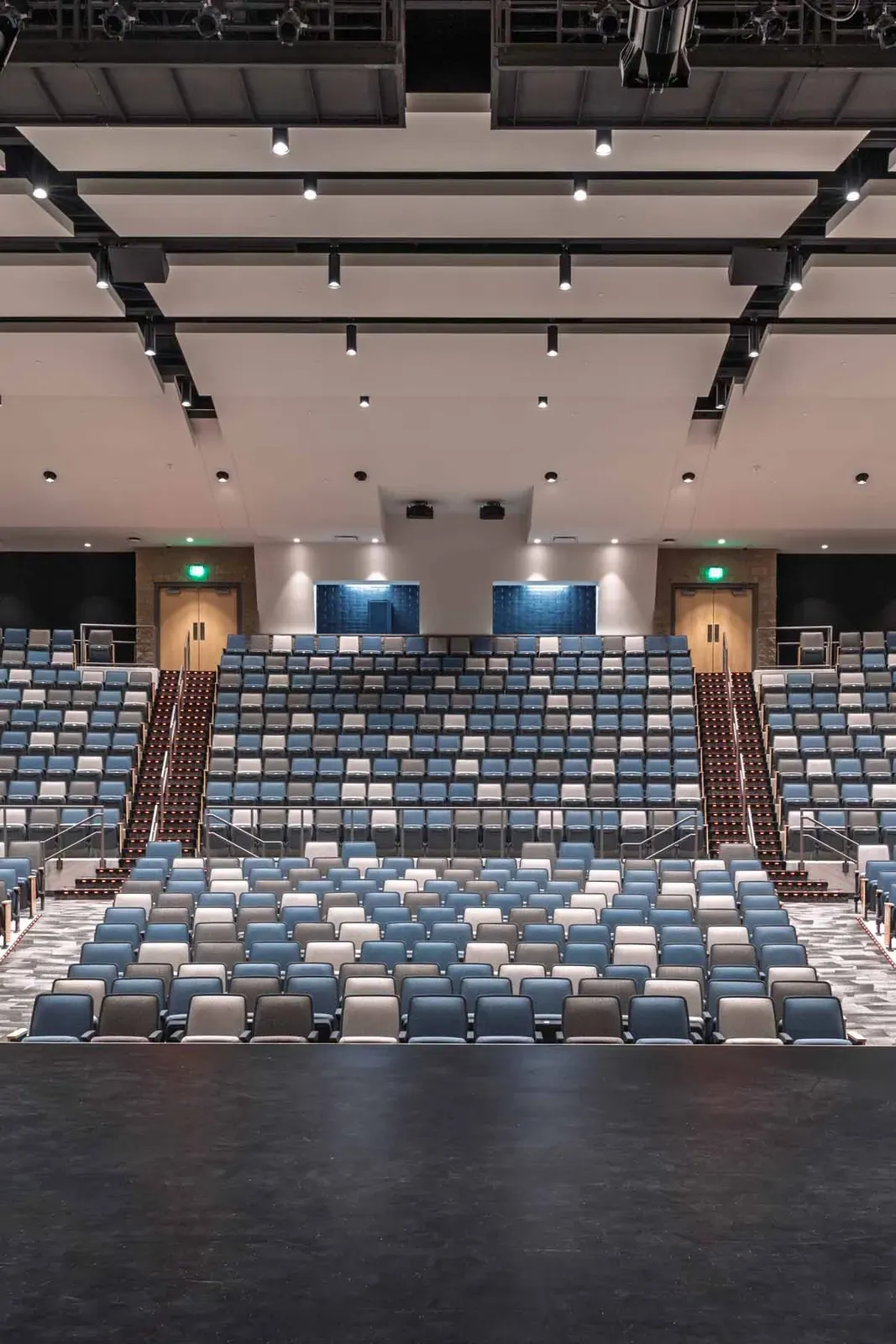 Blue and gray auditorium seating with a rear balcony, seen from the stage.