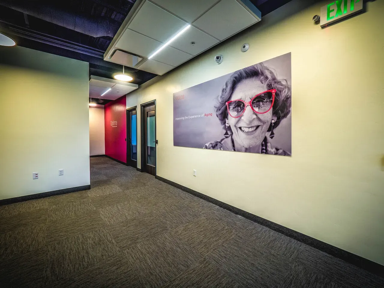 Corridor with a large black-and-white portrait of a smiling woman in red glasses on the wall