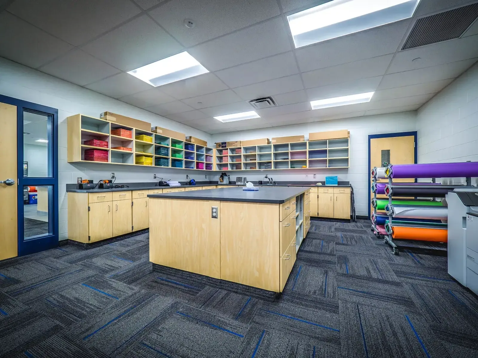 Work room with an island counter, cubby shelving, and rolls of colored paper