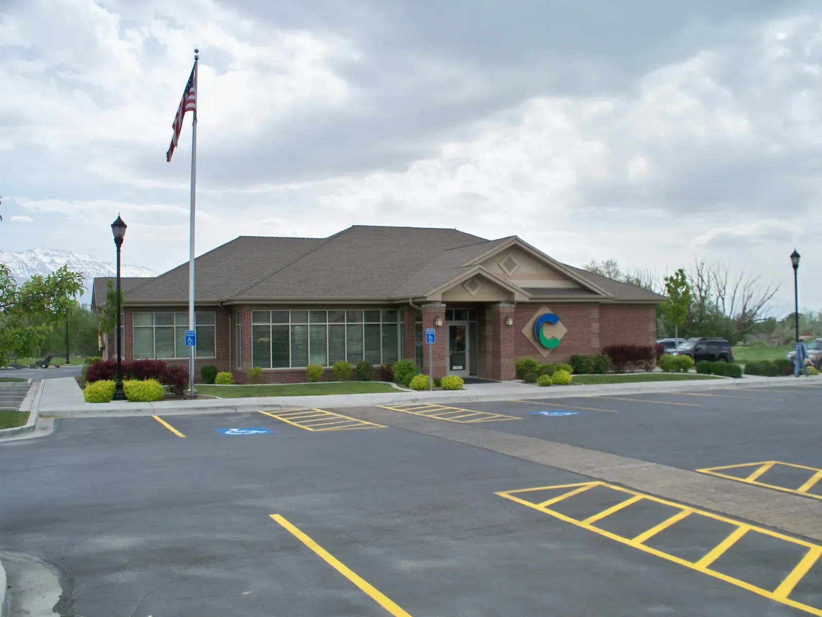 Saratoga branch with brick walls, a flag pole and mountains beyond the parking lot.