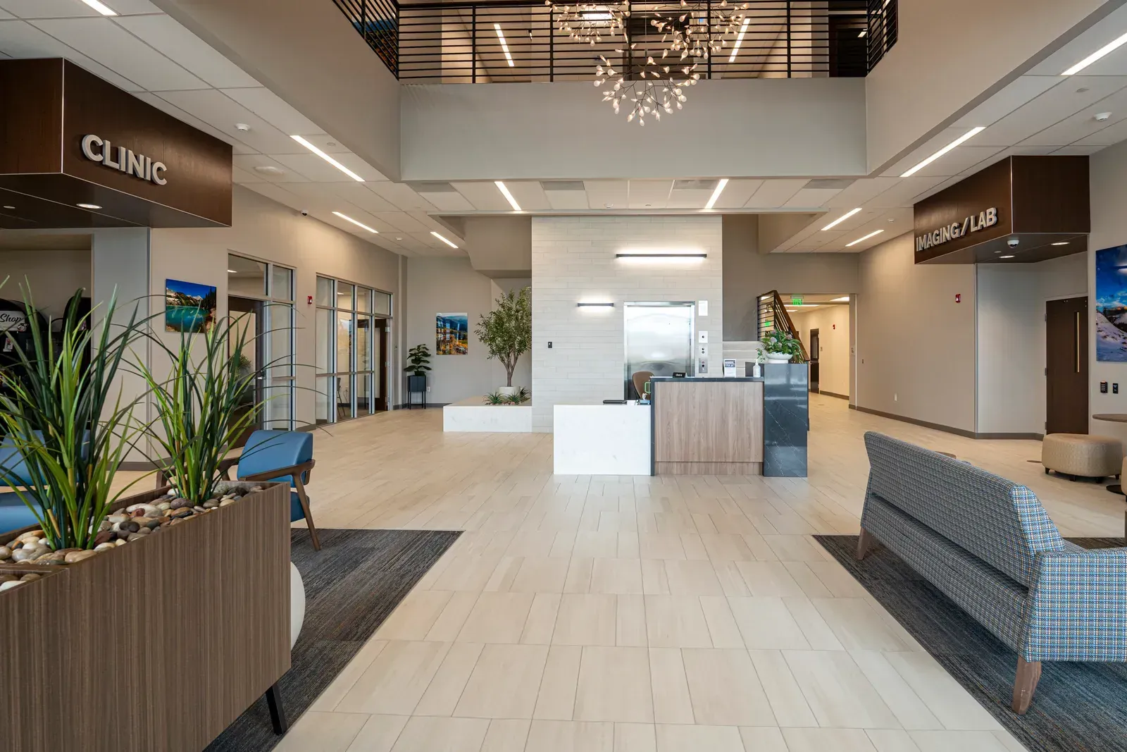 Hospital lobby with a reception desk, Clinic and Imaging/Lab signs, a chandelier and seating.