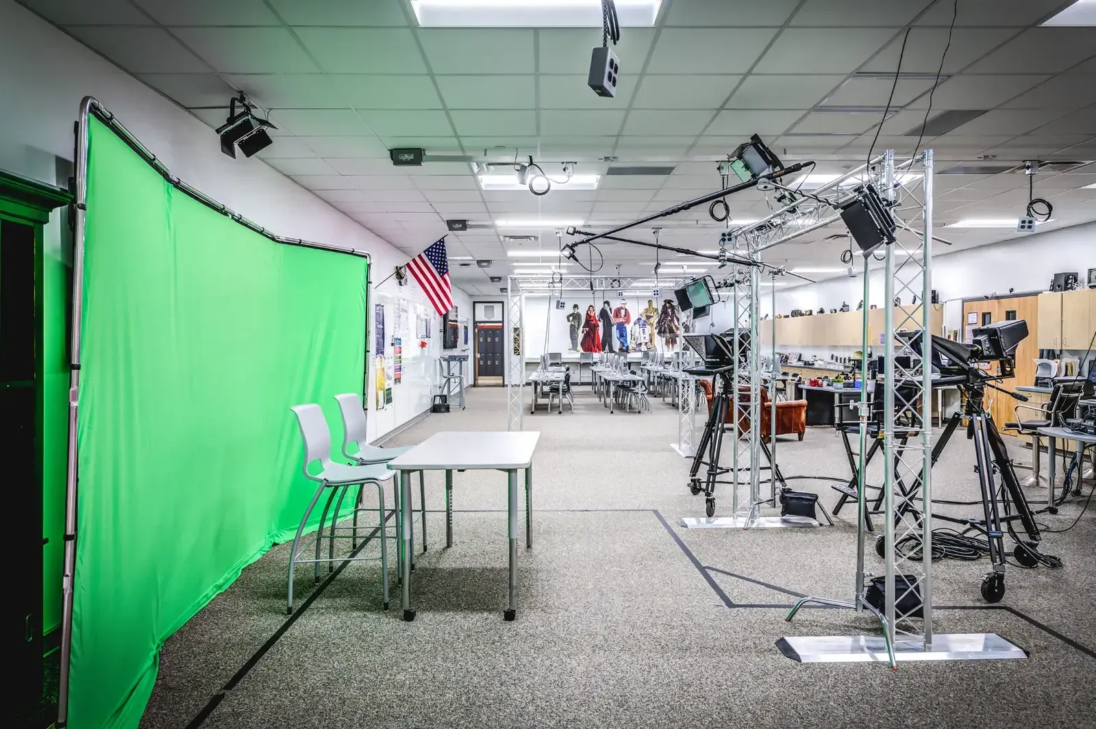 Classroom set up as a media studio with a green screen, studio lights and cameras.