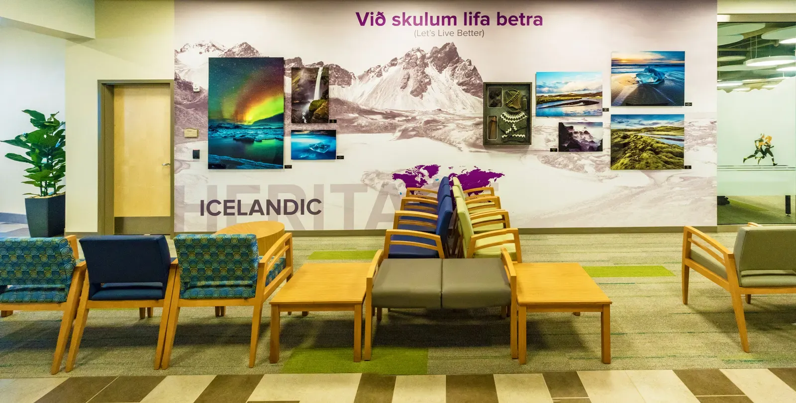 Waiting area with wood and upholstered chairs in front of a wall mural of Icelandic landscape photos.