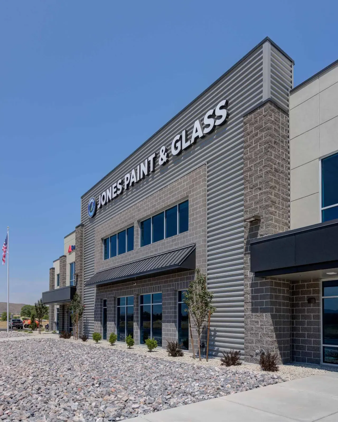 Entrance tower clad in metal siding and masonry with the company sign, landscaped gravel in the foreground