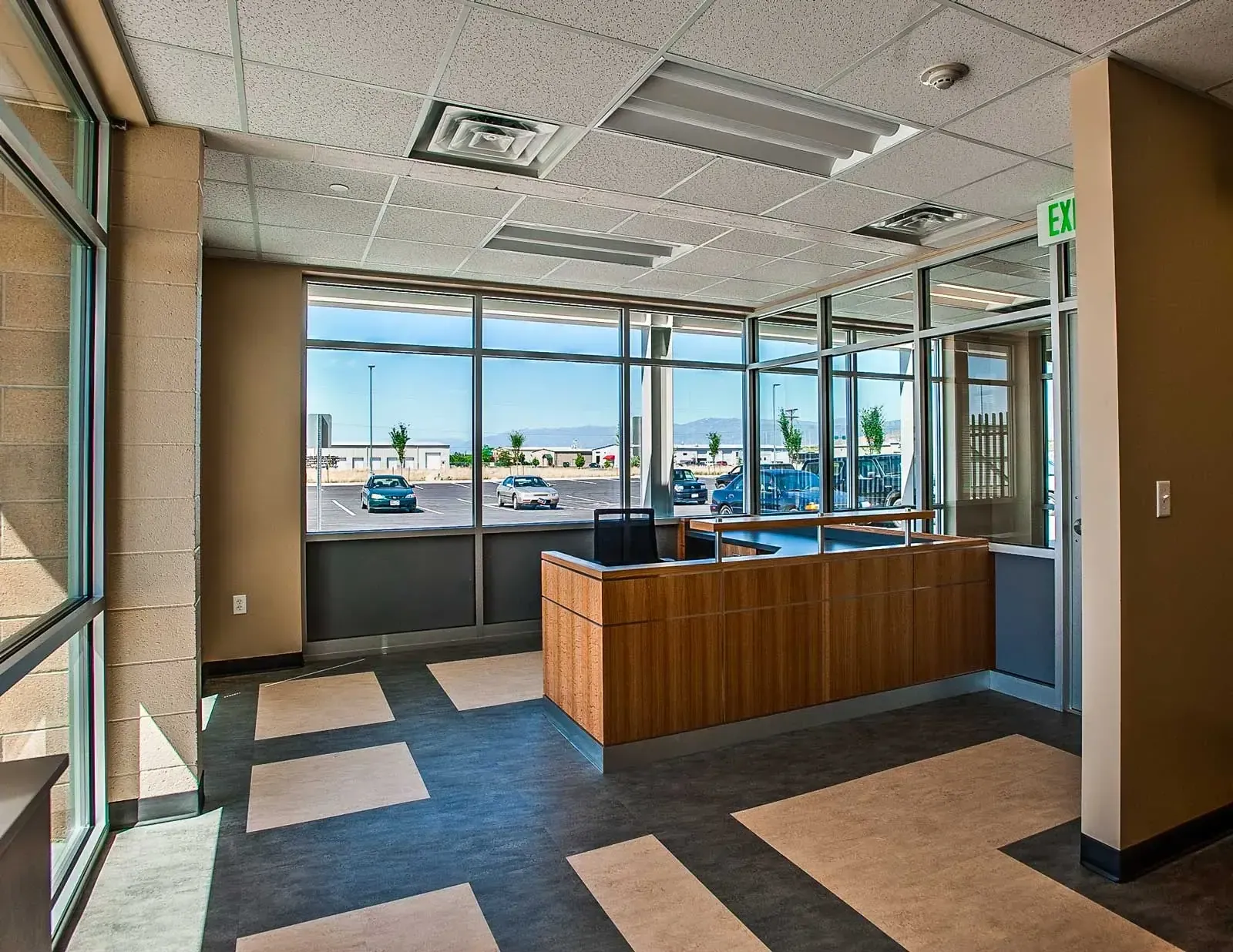Office reception counter with a wood-front desk and large windows onto the parking lot