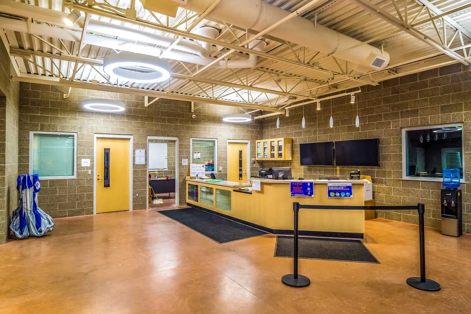 Lobby with a front desk, yellow doors, concrete block walls, and stanchions