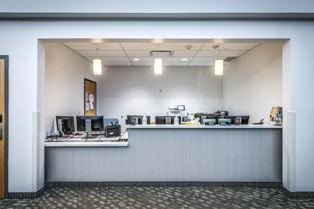 Registration counter with computer stations behind a recessed opening.