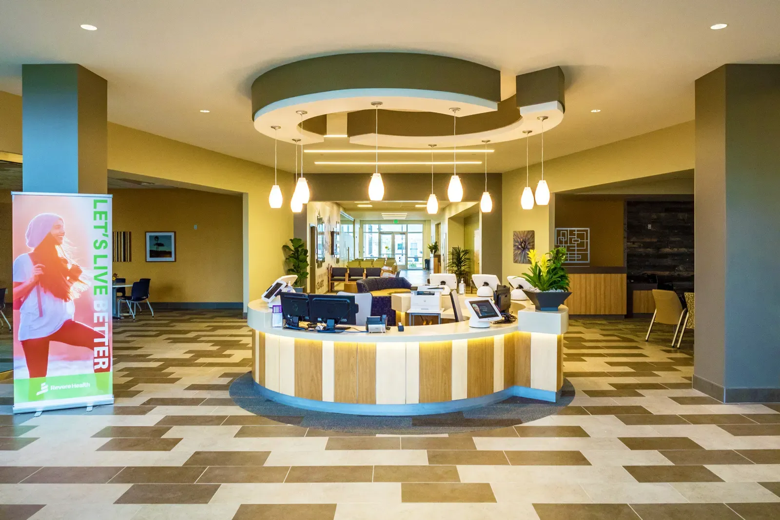 Round reception desk under a circular ceiling soffit with pendant lights, over a tiled floor.