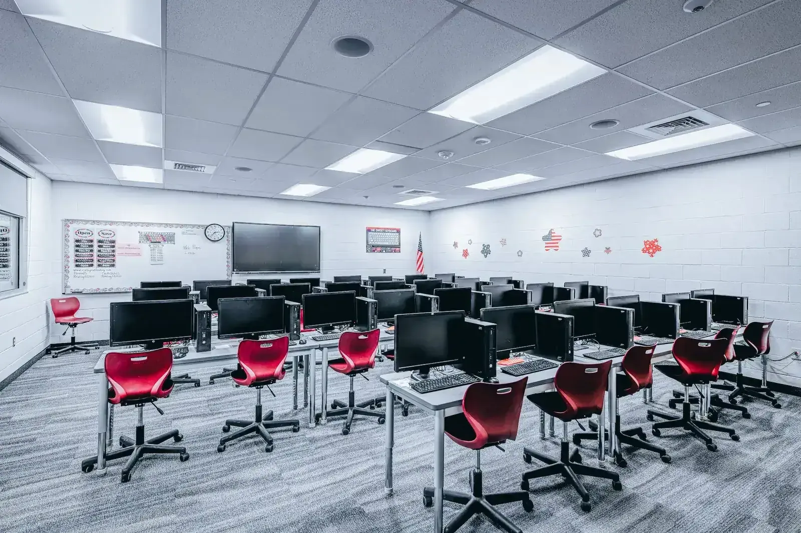 Computer lab with rows of desktop monitors and red rolling chairs