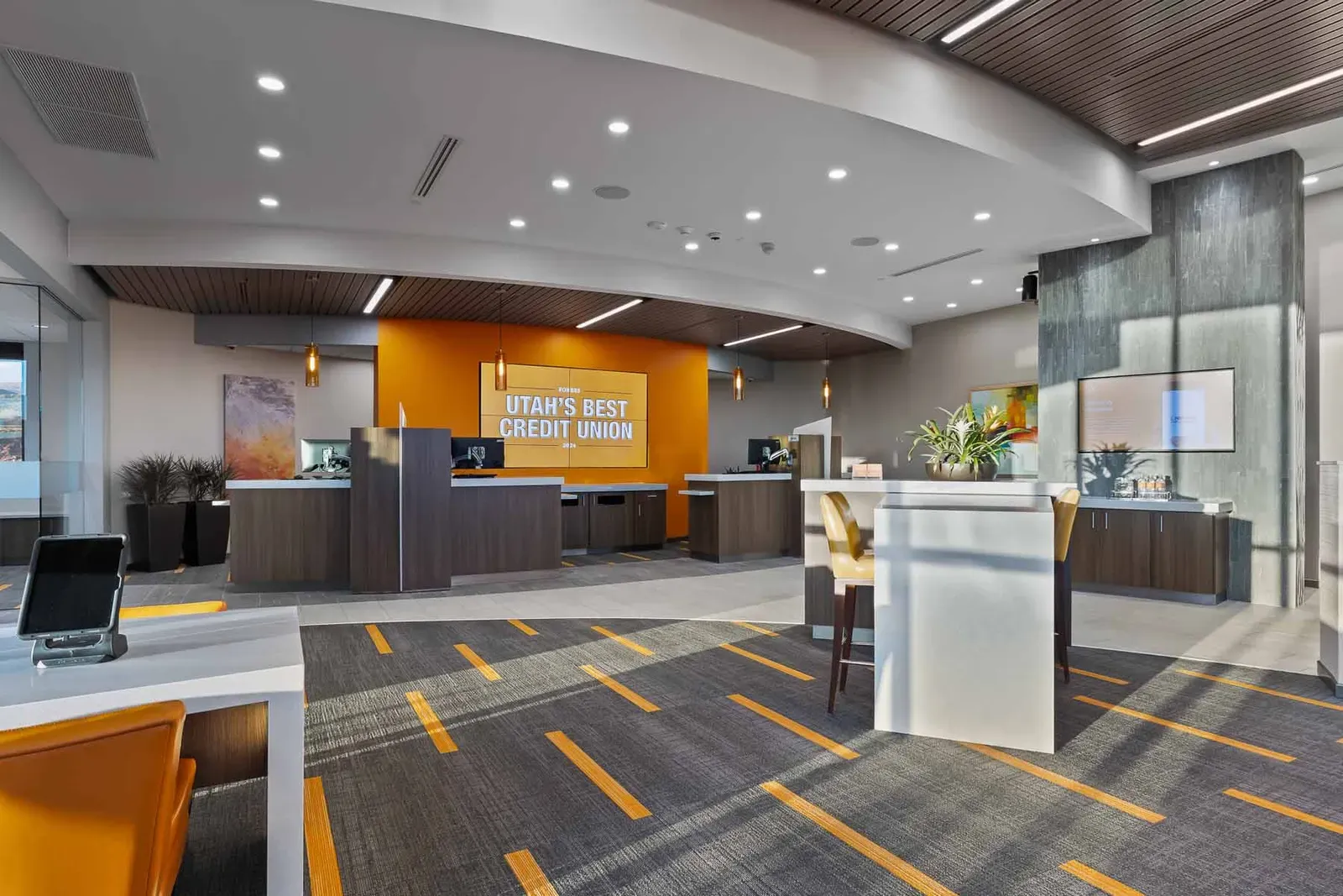 Teller area with a curved ceiling and an orange wall reading Utah's Best Credit Union.