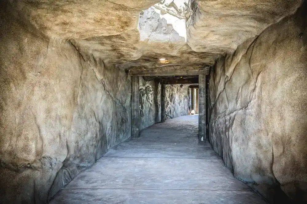 Inside the rock-walled tunnel, with timber supports and an opening in the ceiling letting in light