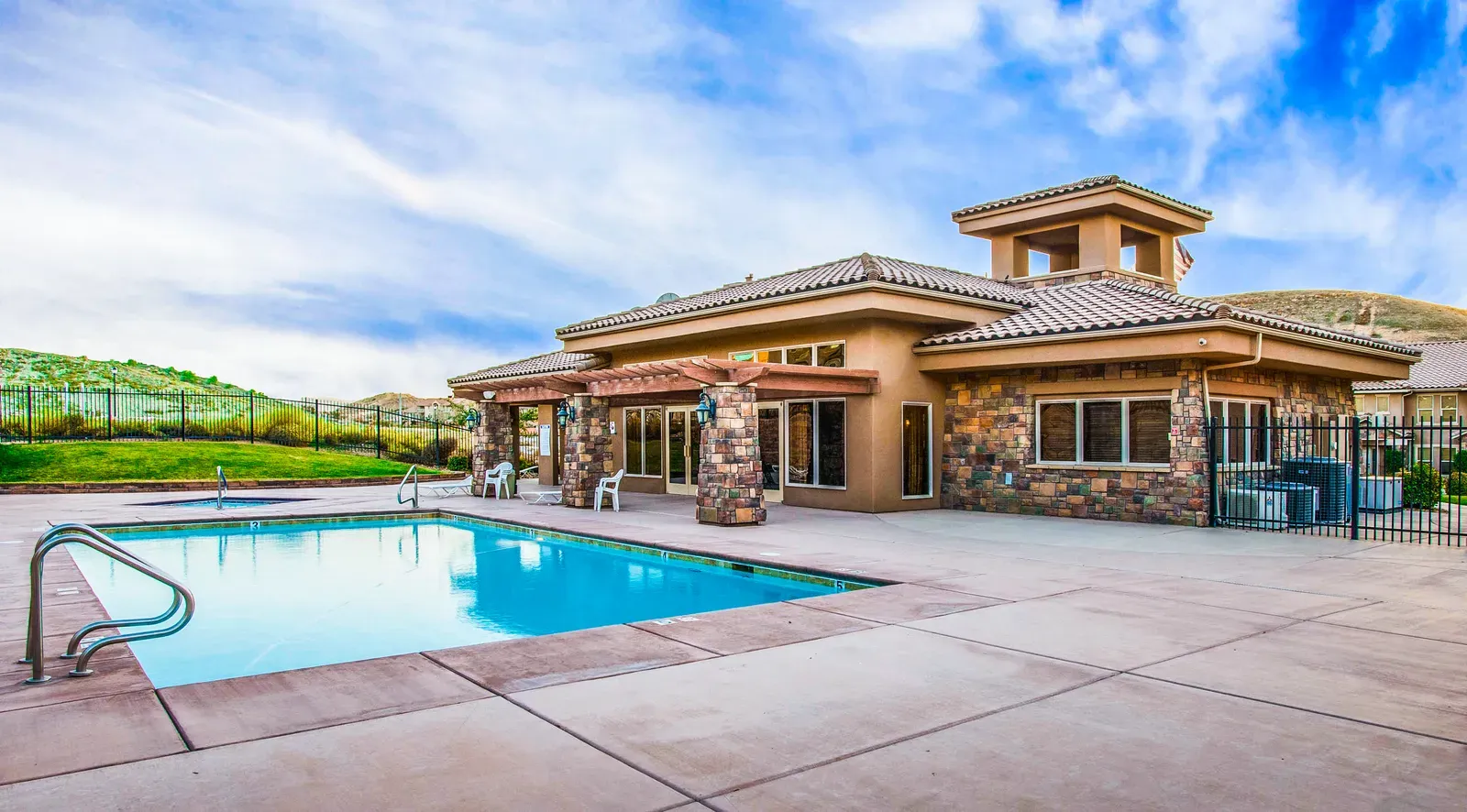 Swimming pool beside the clubhouse, a stone-trimmed building with a tile roof and tower