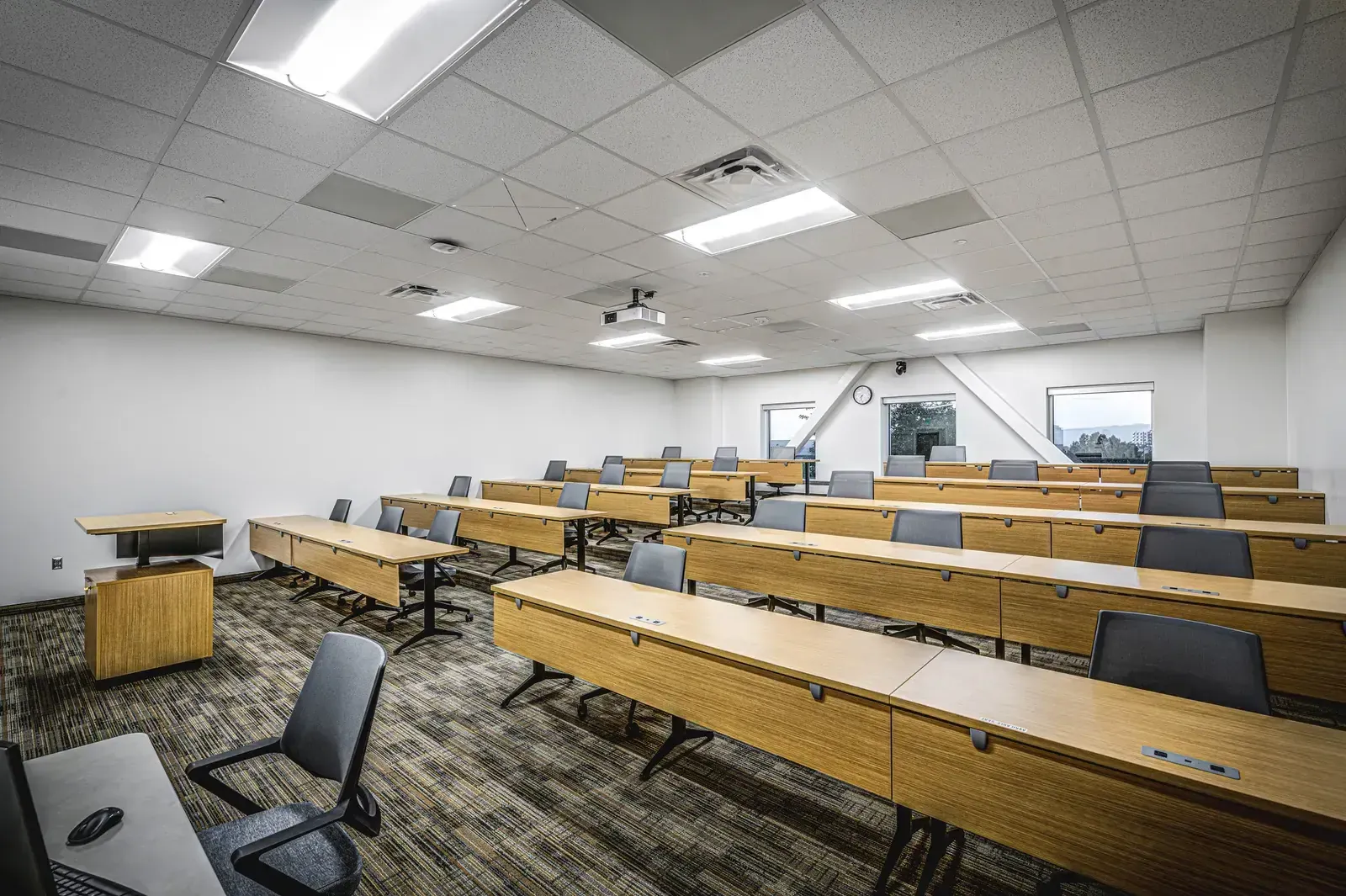 Classroom with long wood-front tables and gray chairs