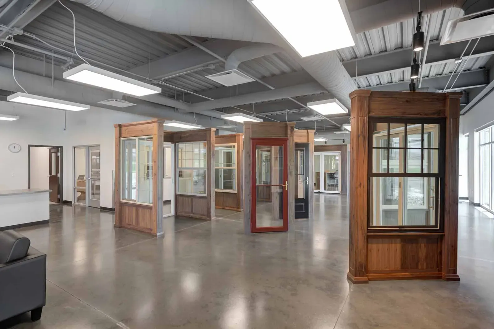 Window and door display area with wood-framed sample units on a polished concrete floor