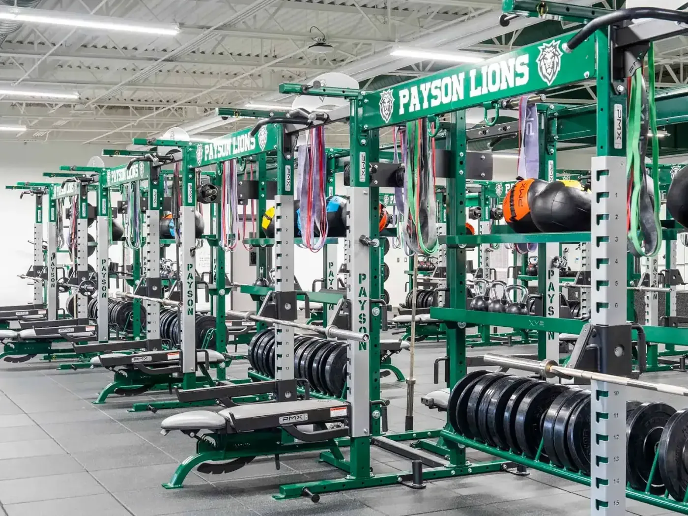 Weight room with green Payson Lions lifting racks and weight plates