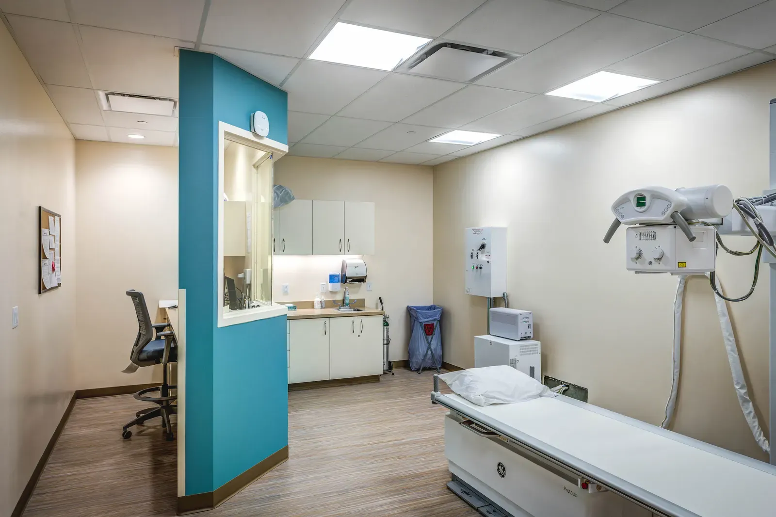 Exam room with an X-ray arm, an exam table and a teal partition wall