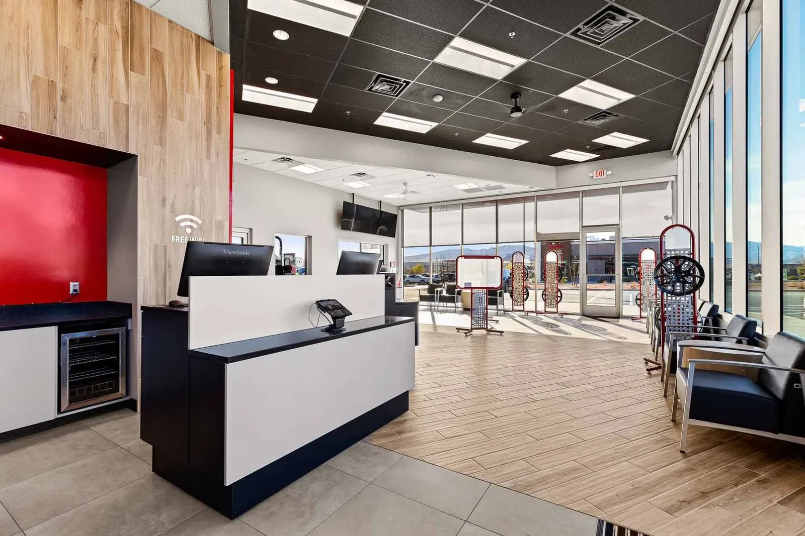Sales counter and waiting area with wood-look flooring, a red accent wall and large windows