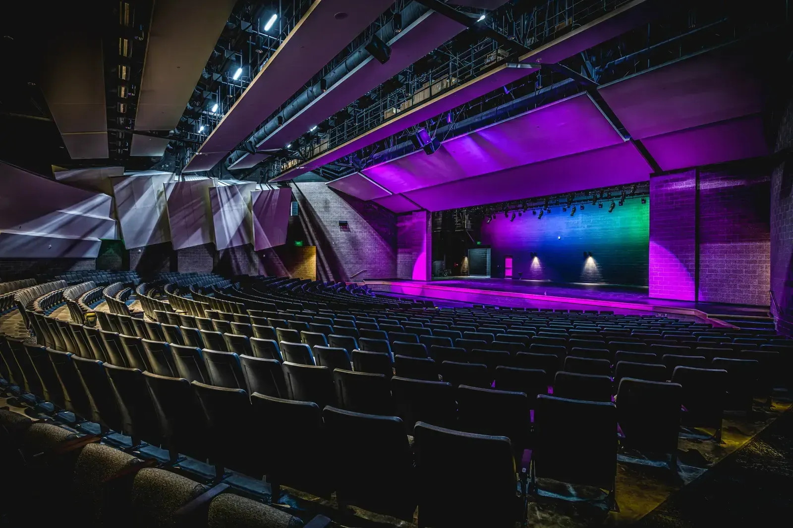 Auditorium seating facing a stage lit in purple and green.