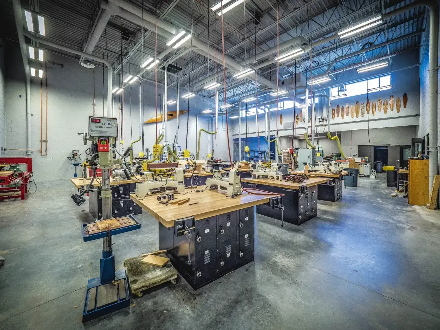 Wood shop with workbenches, lathes and woodworking machines under high bay lighting