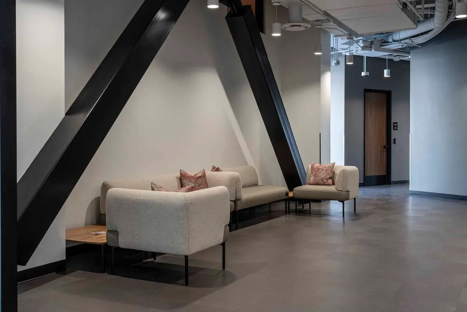 Seating area with gray sofas beneath large black diagonal steel braces.