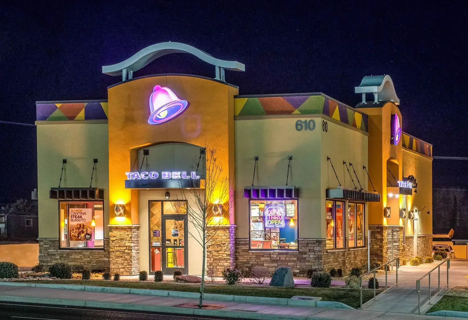 Taco Bell exterior at night with the lit bell sign above the entry.