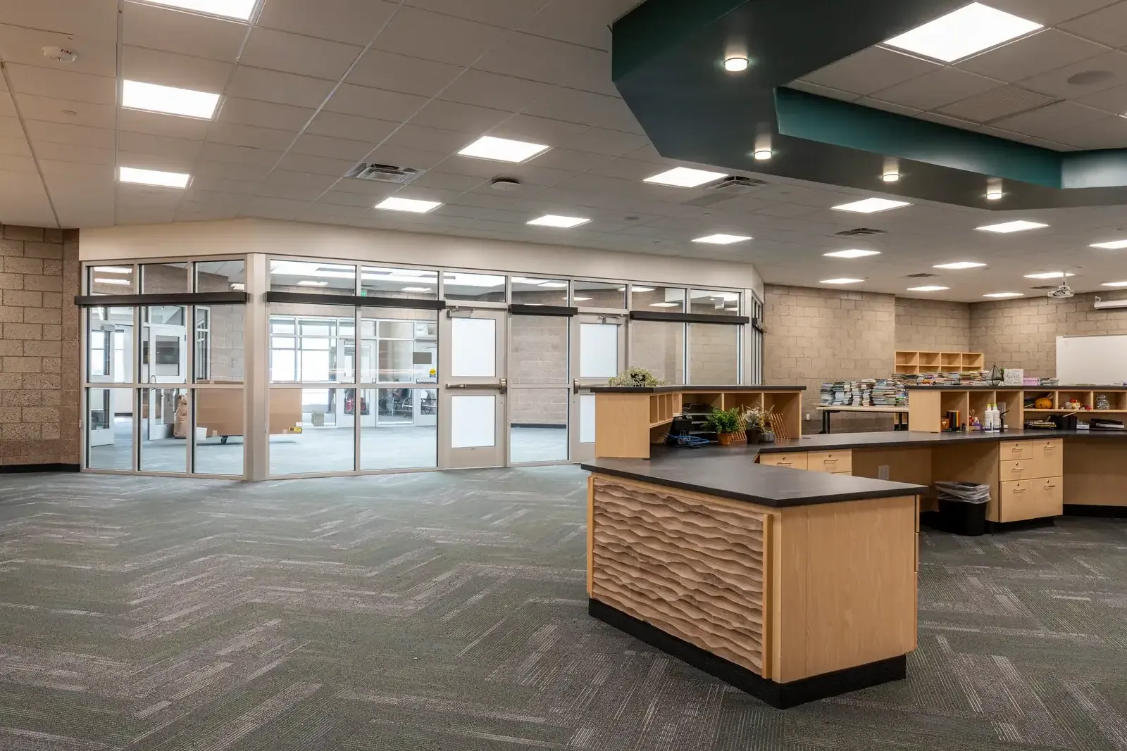 Wood-fronted service desk with a wavy carved panel, shelving and a glass wall at one side.