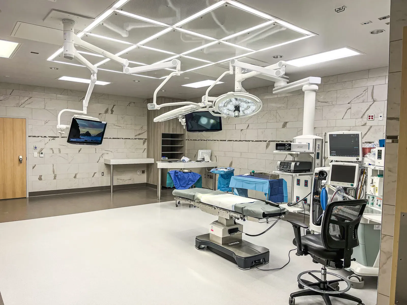Operating room with a surgical table, ceiling-mounted lights, and monitors