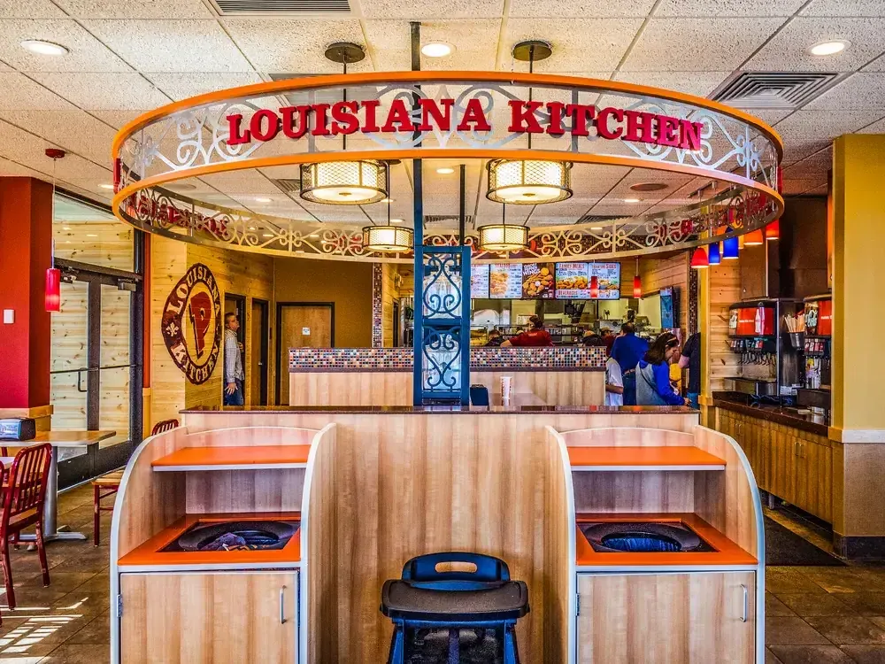 Ring-shaped Louisiana Kitchen sign with decorative ironwork hanging over the counter, with built-in seating in front.