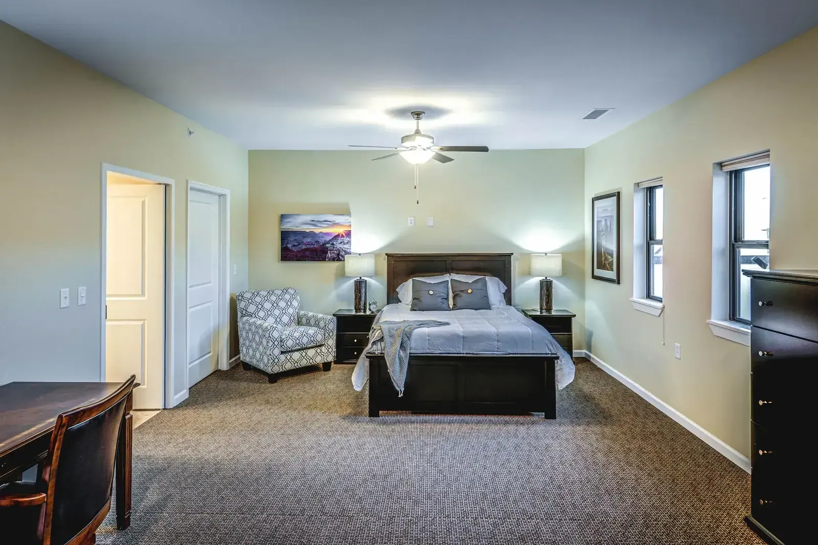 Resident bedroom with a double bed, an armchair and framed artwork.