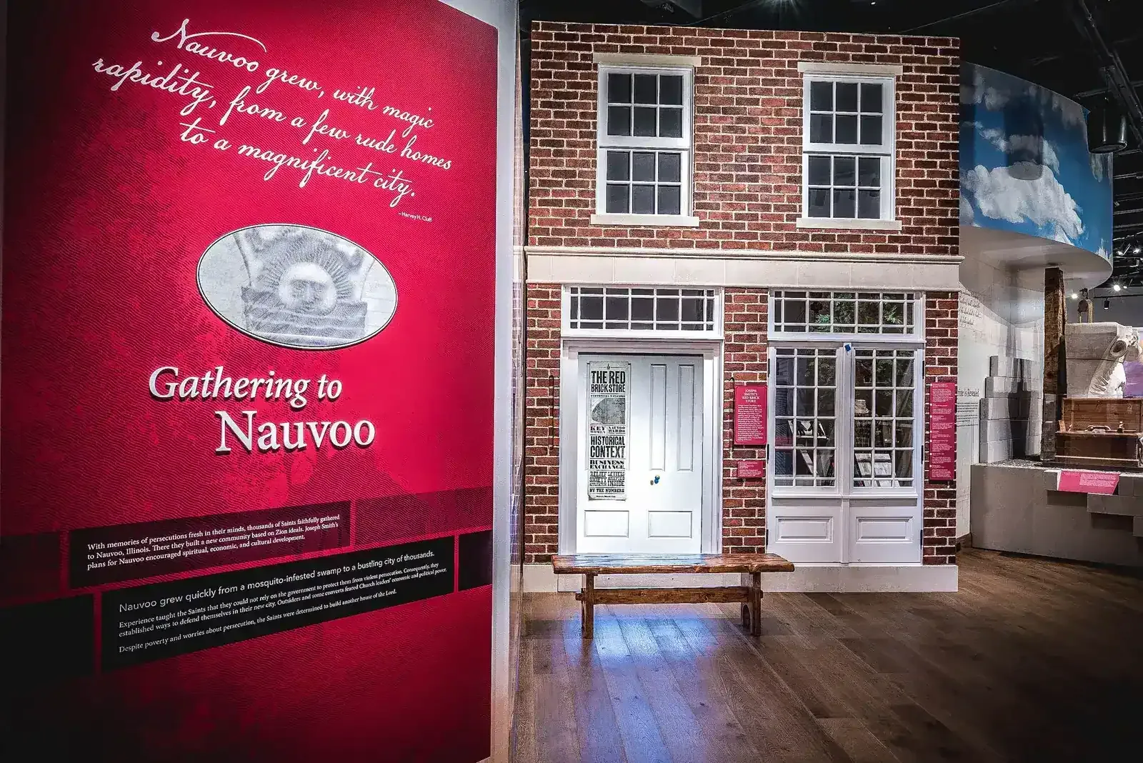 Exhibit with a recreated brick storefront and a red wall panel titled "Gathering to Nauvoo"